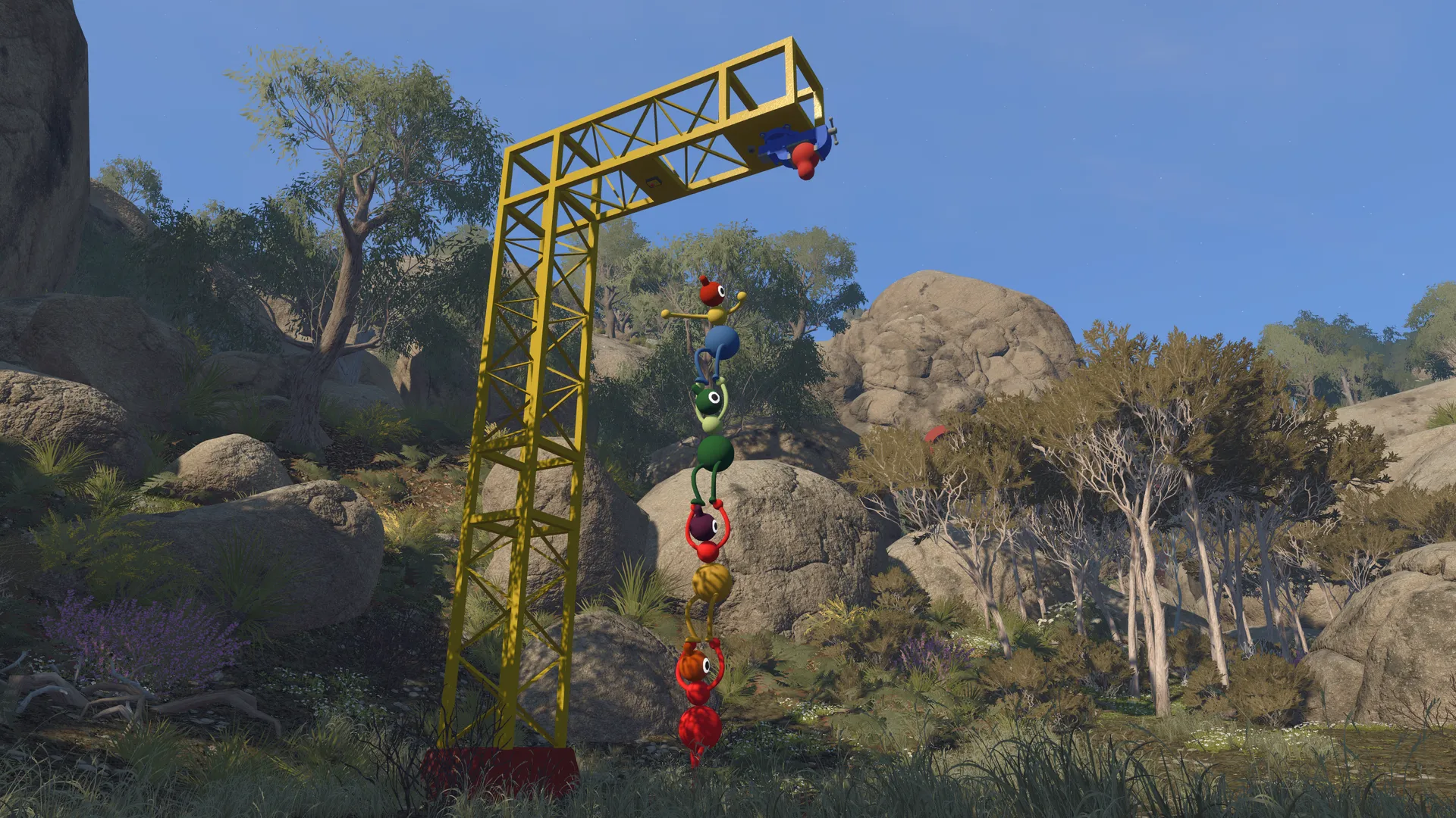 Friends dangling in a chain beneath a yellow crane.